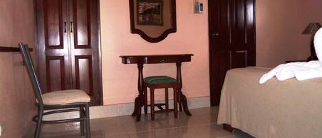Un dormitorio con una cama, una silla, una mesita y una puerta.