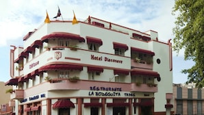 A multi-story hotel with balconies, a restaurant on the ground floor, and a clear sky. - Hotel Discovery (Santo Domingo)