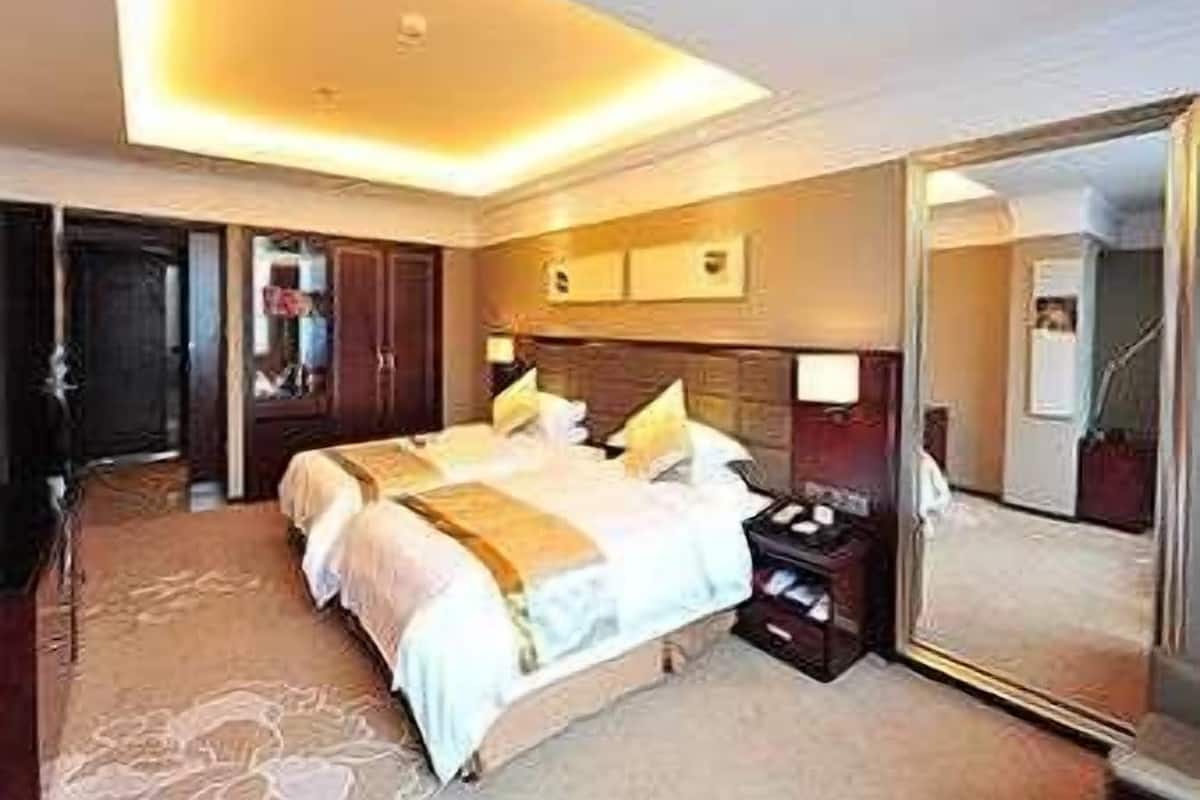 Una habitación de hotel con una cama grande, una mesita de noche, un espejo y un armario.
