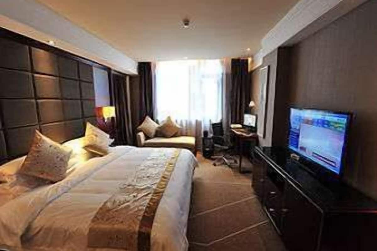 Una habitación de hotel con una cama grande, un escritorio con computadora y televisión.