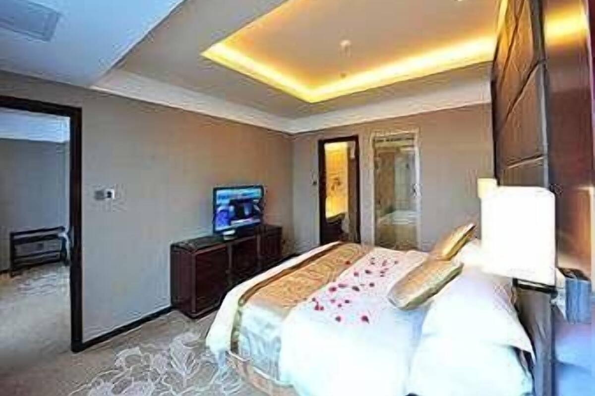 Una habitación de hotel con cama, televisión, escritorio y espejo.