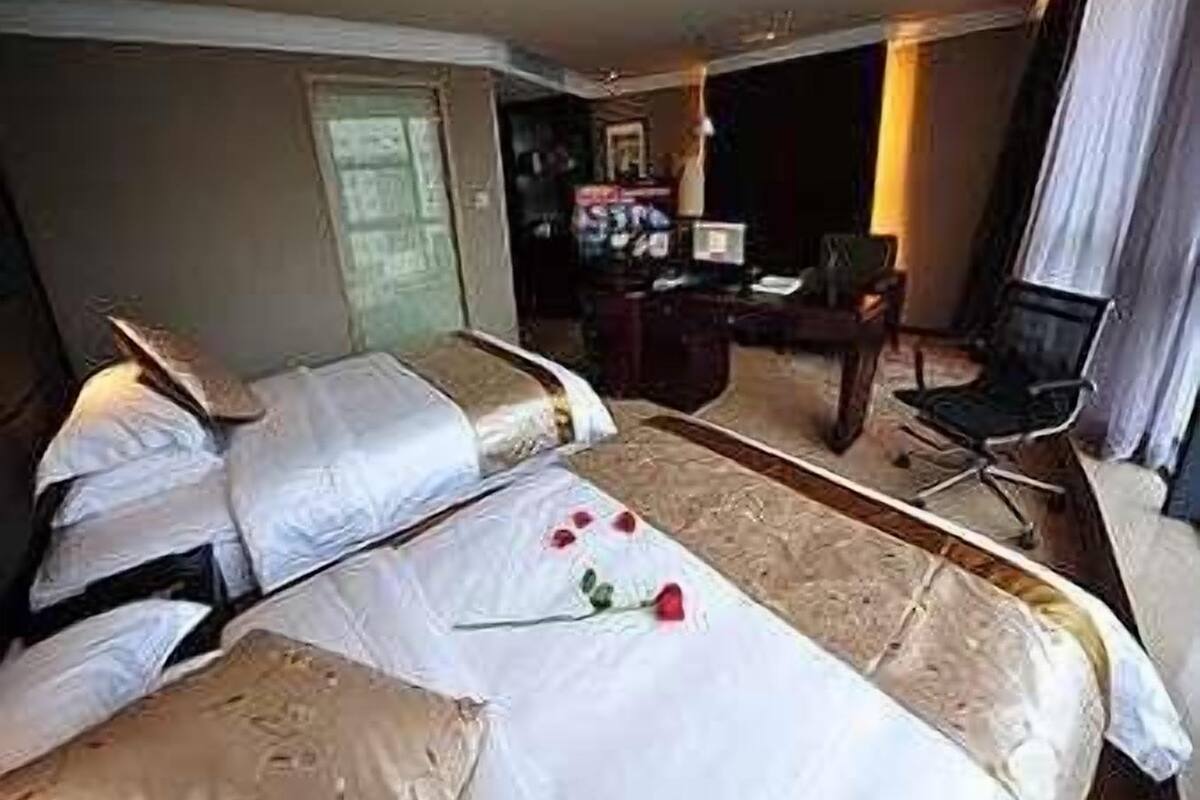 Una habitación de hotel con dos camas, un escritorio, una silla y una lámpara.