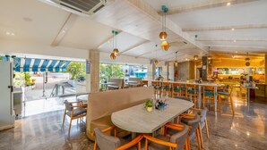 Een ruim restaurant met hoge plafonds, houten meubels en hanglampen.