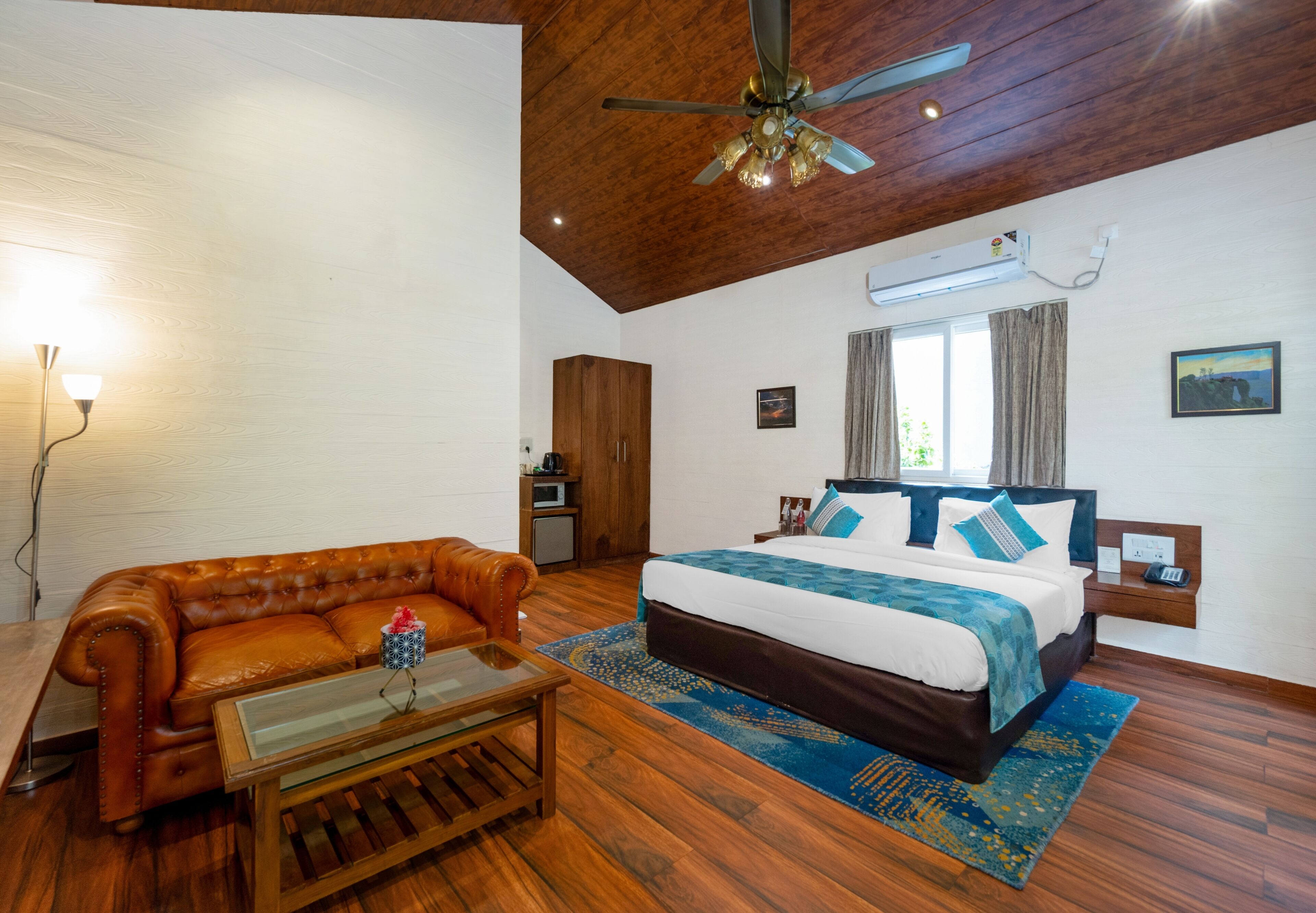 A bedroom with a bed, a wooden ceiling, a ceiling fan, a window, and a nightstand.