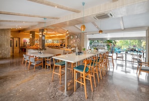 A spacious restaurant with high ceilings, wooden chairs, and a bar area. - Orchid Hotel Panchgani (Mahabaleshwar)