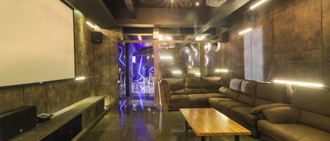 A modern lounge with a large screen, leather couches, and ambient lighting.