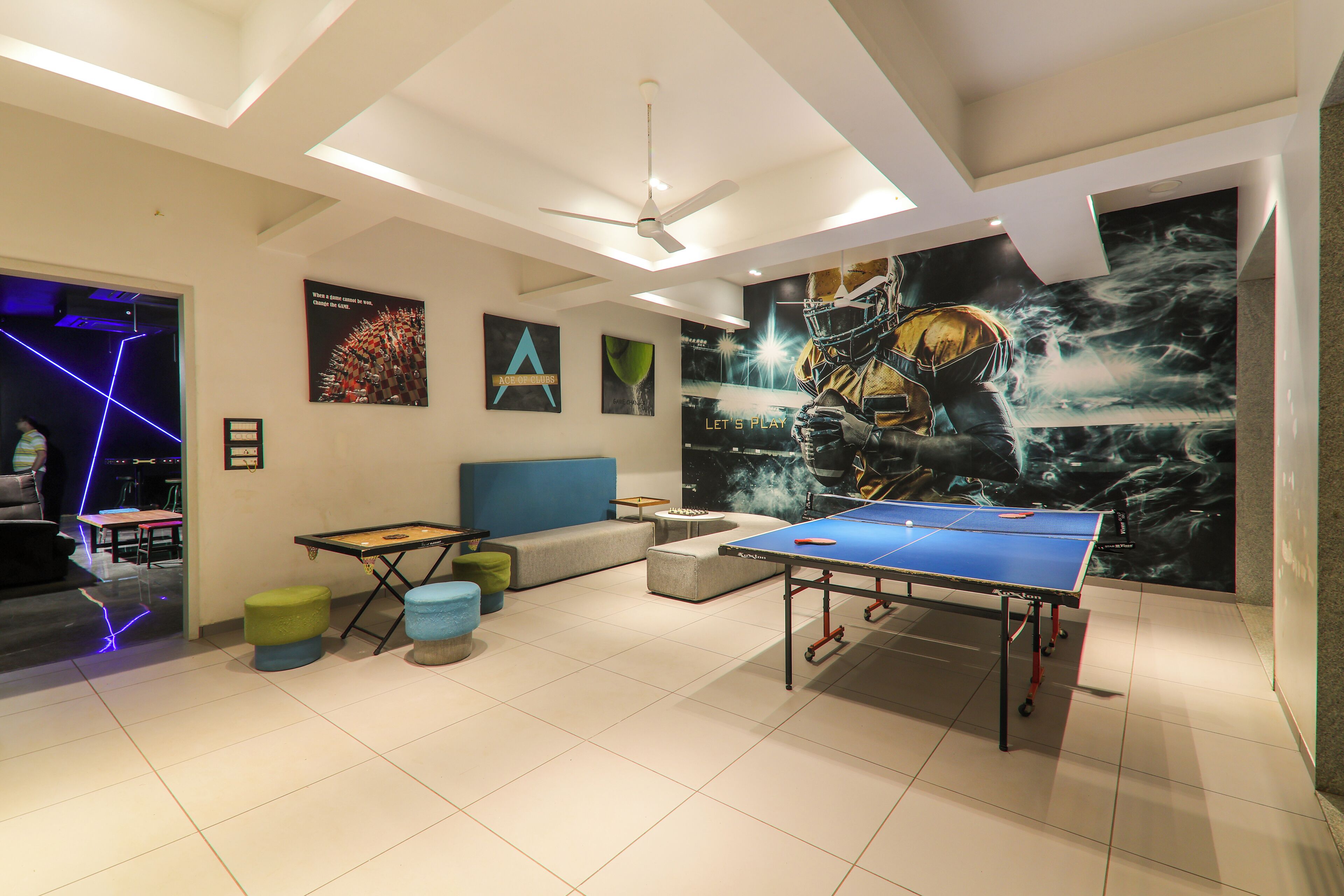 A modern room with a ping pong table, a ceiling fan, and a large mural on the wall.