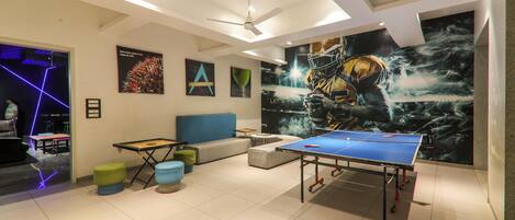 A modern room with a ping pong table, a ceiling fan, and a large mural on the wall.