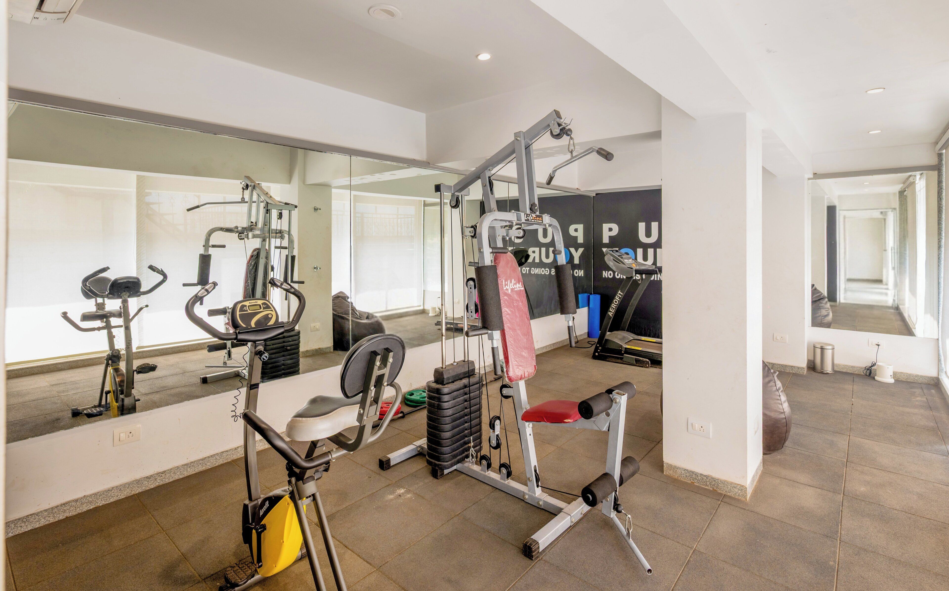 A gym with exercise equipment, a large mirror, and a treadmill.