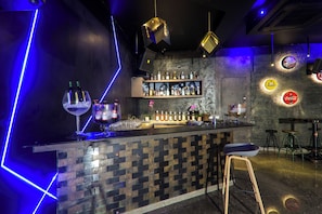 A bar area with a tiled counter, stools, and a variety of bottles and glasses. - Orchid Hotel Panchgani (Mahabaleshwar)