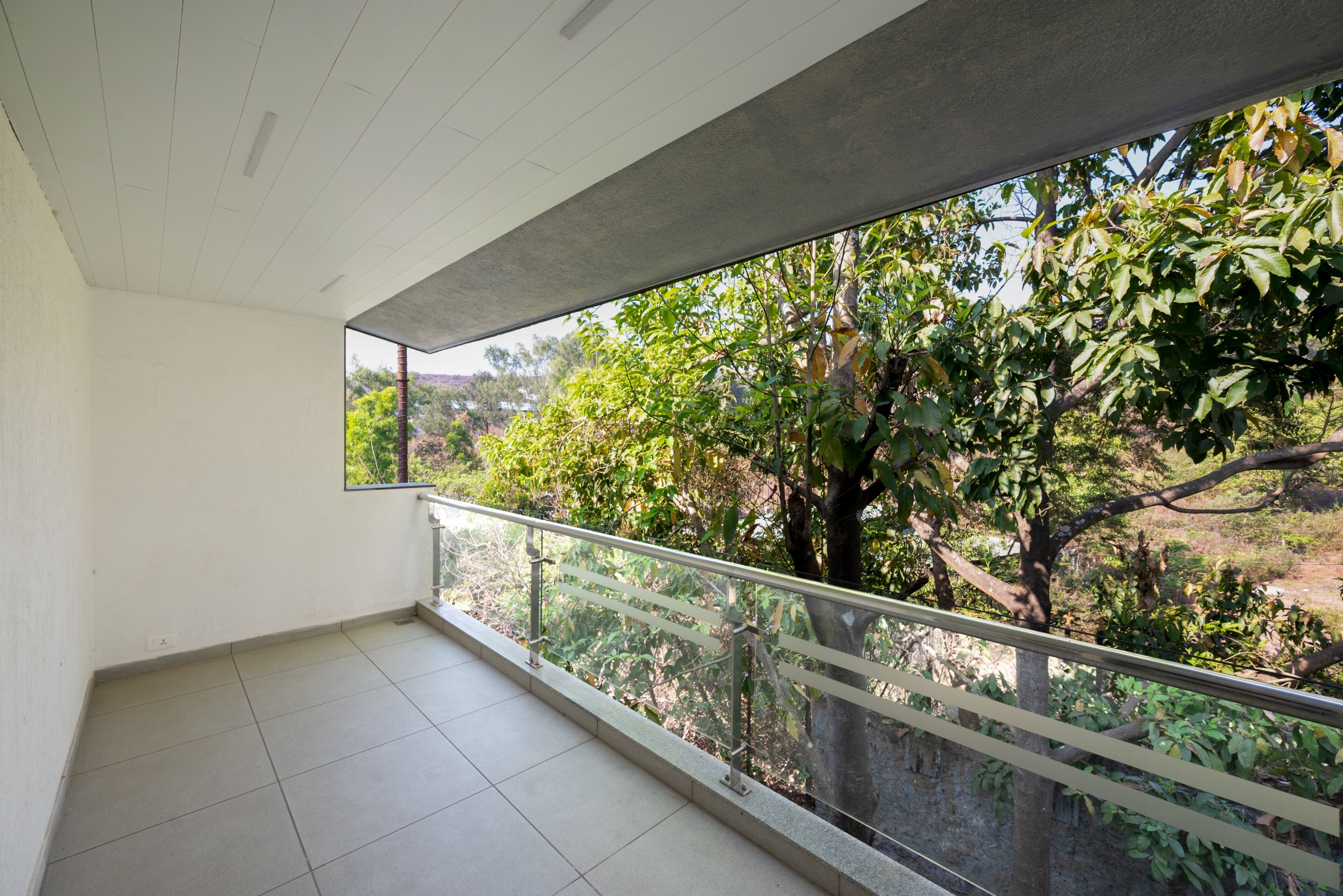 A balcony with a view of trees and a clear sky.
