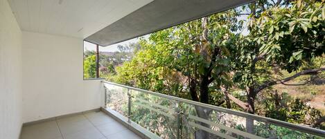 A balcony with a view of trees and a clear sky.