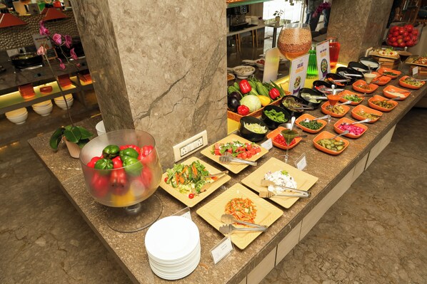 A buffet with various dishes and a large bowl of fruit. - Orchid Hotel Panchgani (Mahabaleshwar)