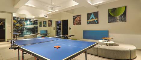 A spacious room with a ping pong table, a sofa, and a small table with a chess set.