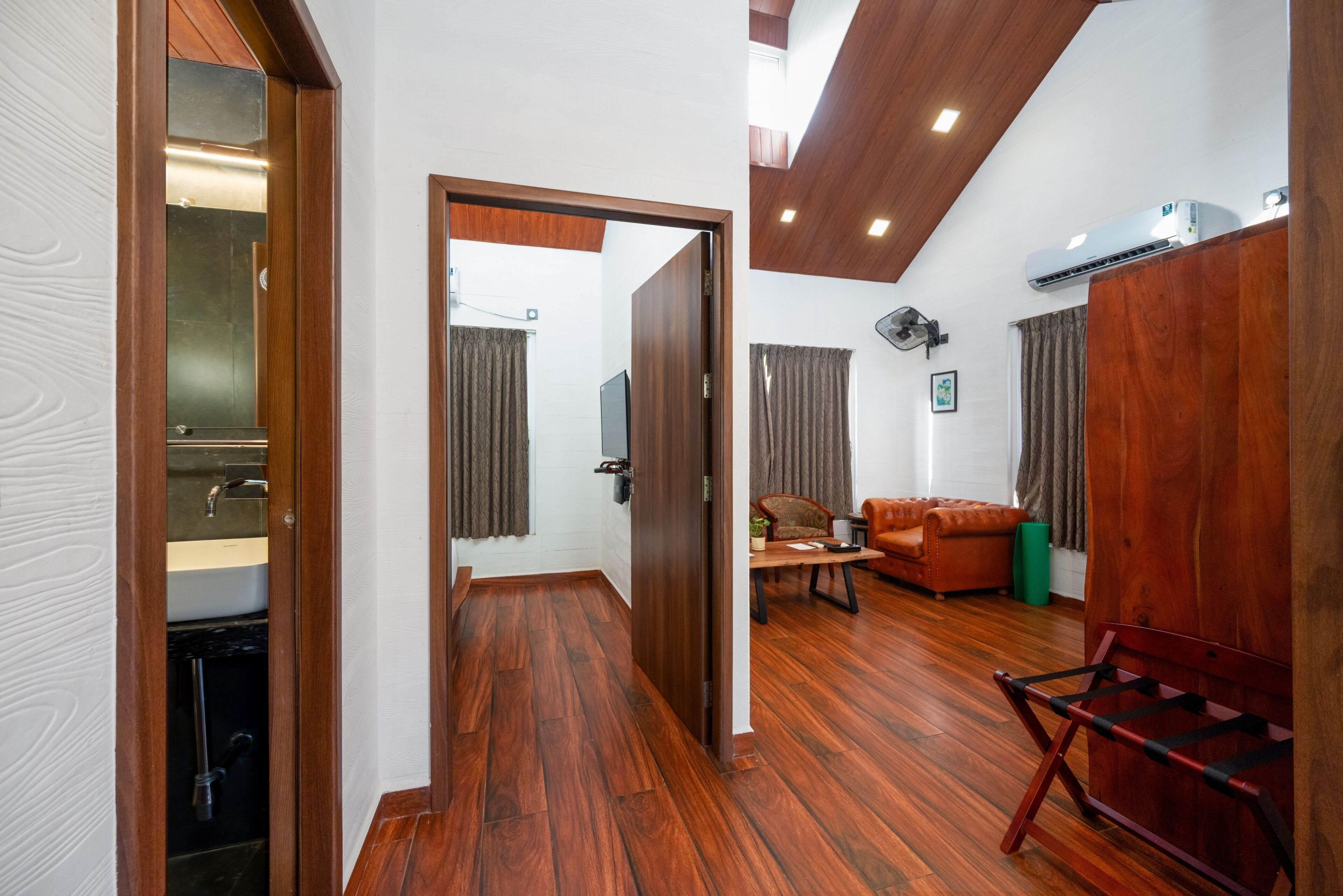 A modern living room with a wooden floor, a sofa, a coffee table, and an air conditioning unit.