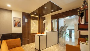Una moderna zona de recepción con suelo de mármol, paneles de madera y asientos color naranja.