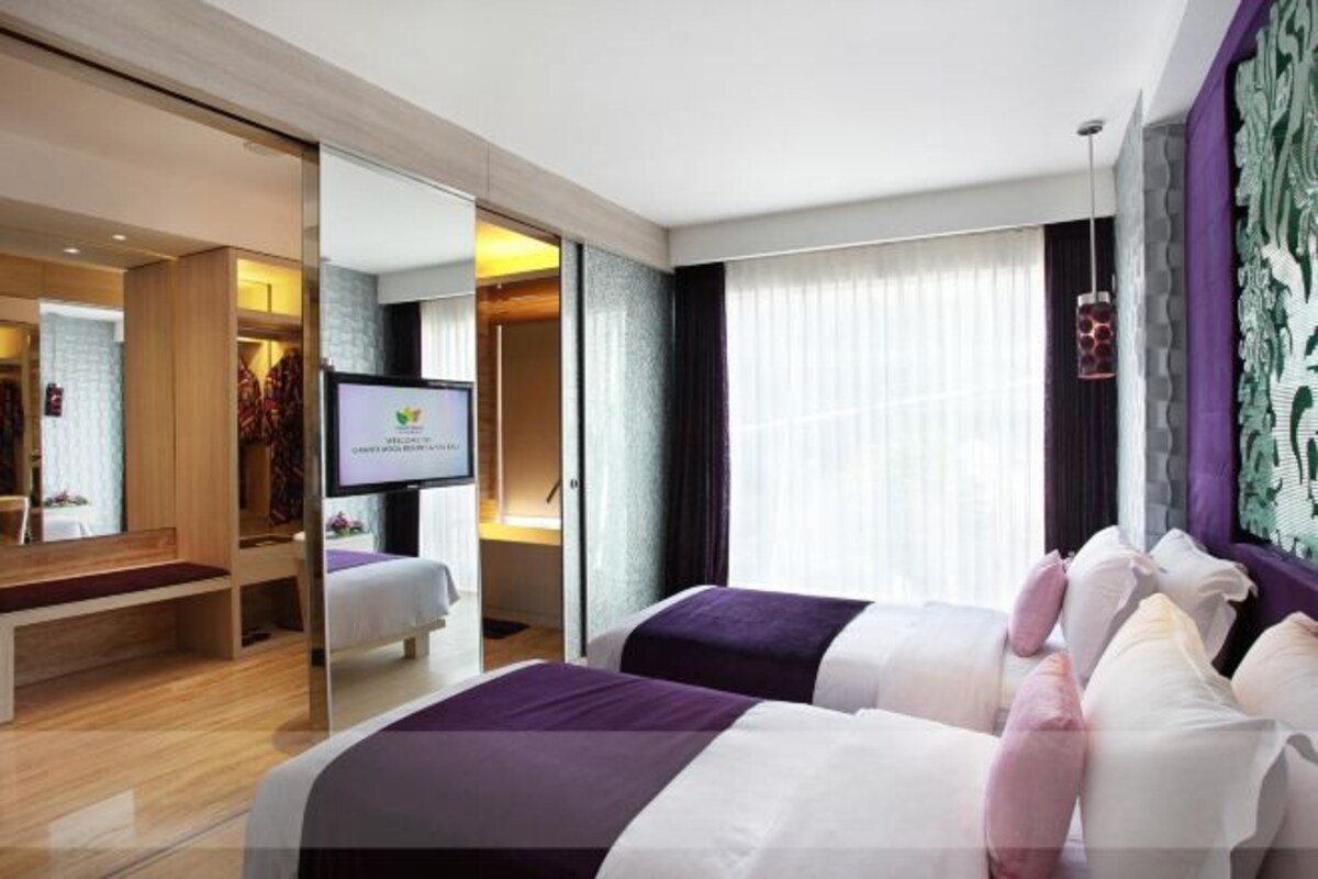 A hotel room with two beds, a TV, a desk, and a wardrobe.