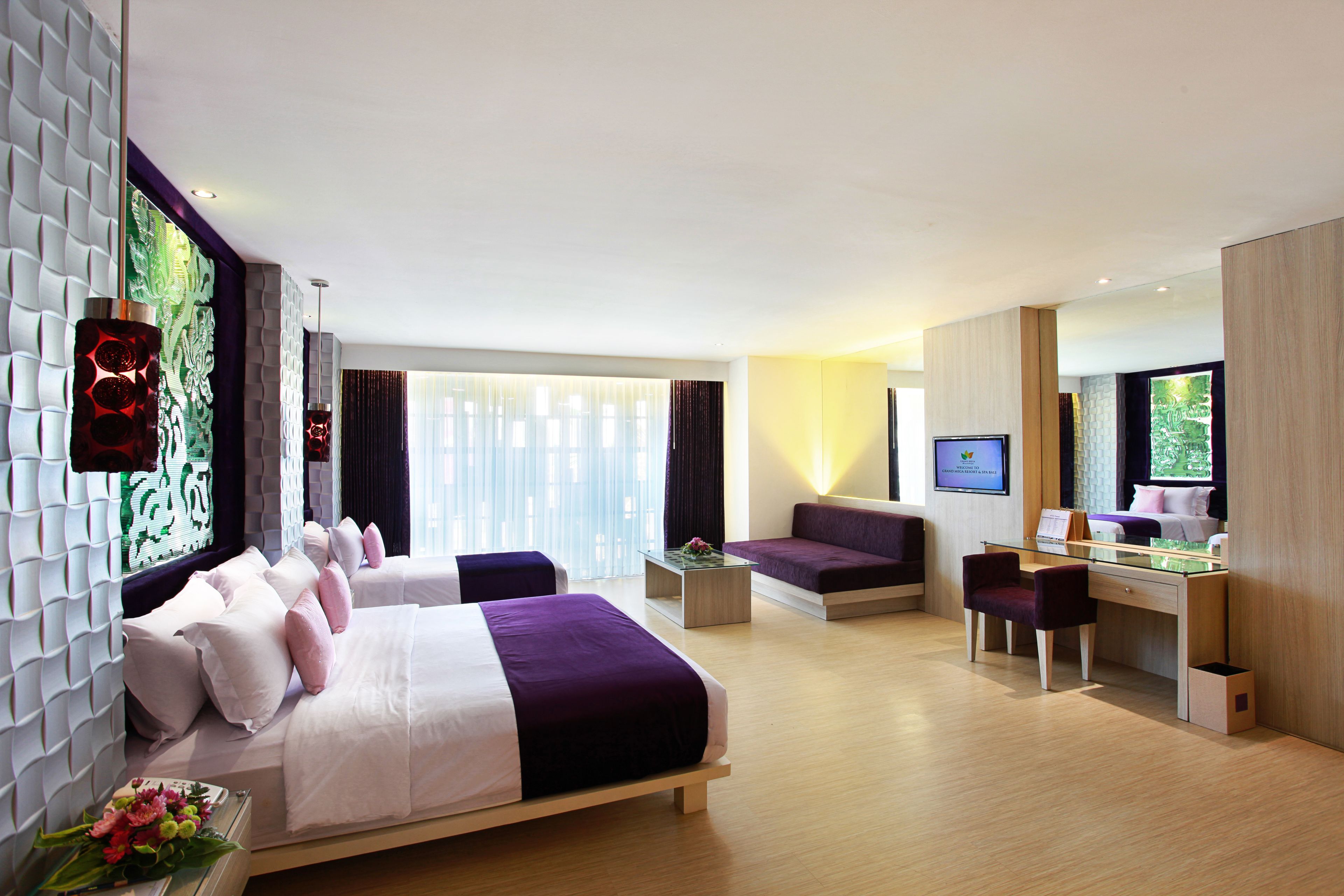 A modern hotel room with a large bed, a desk, a sofa, and a television.