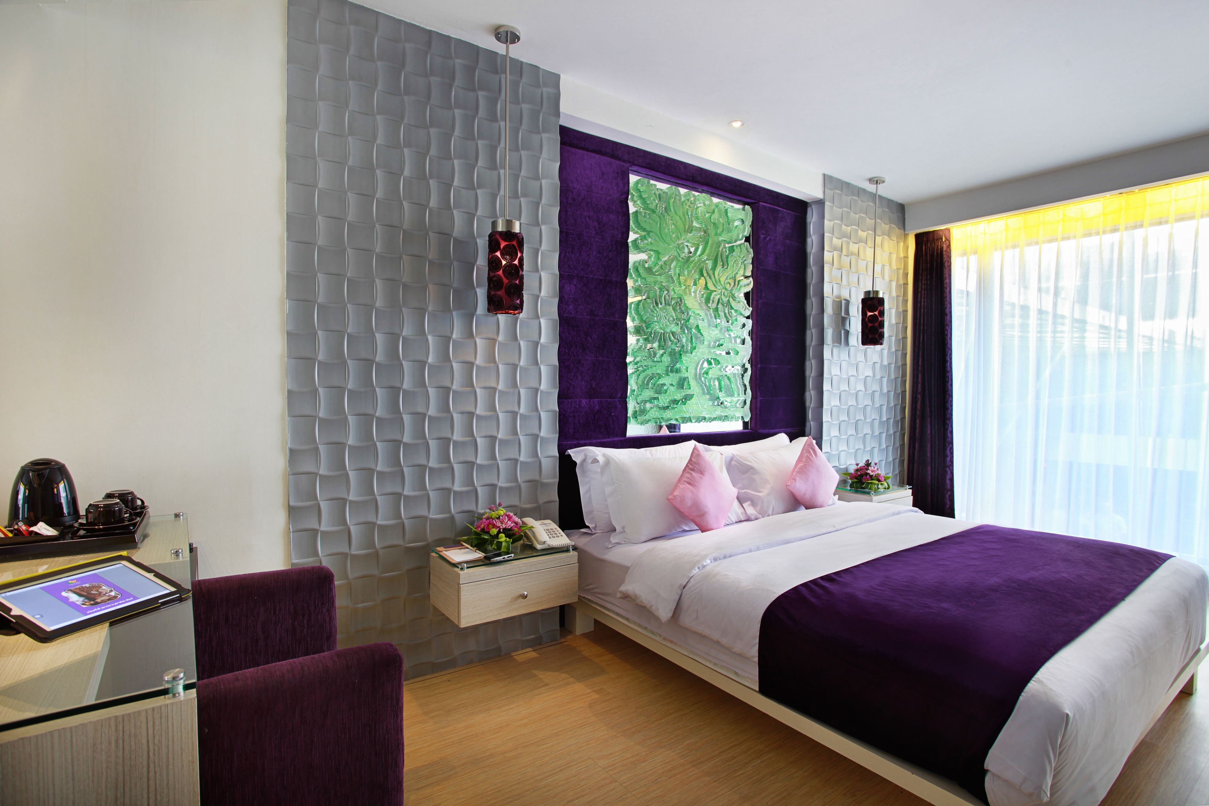 A modern hotel room with a bed, a desk, and a chair.