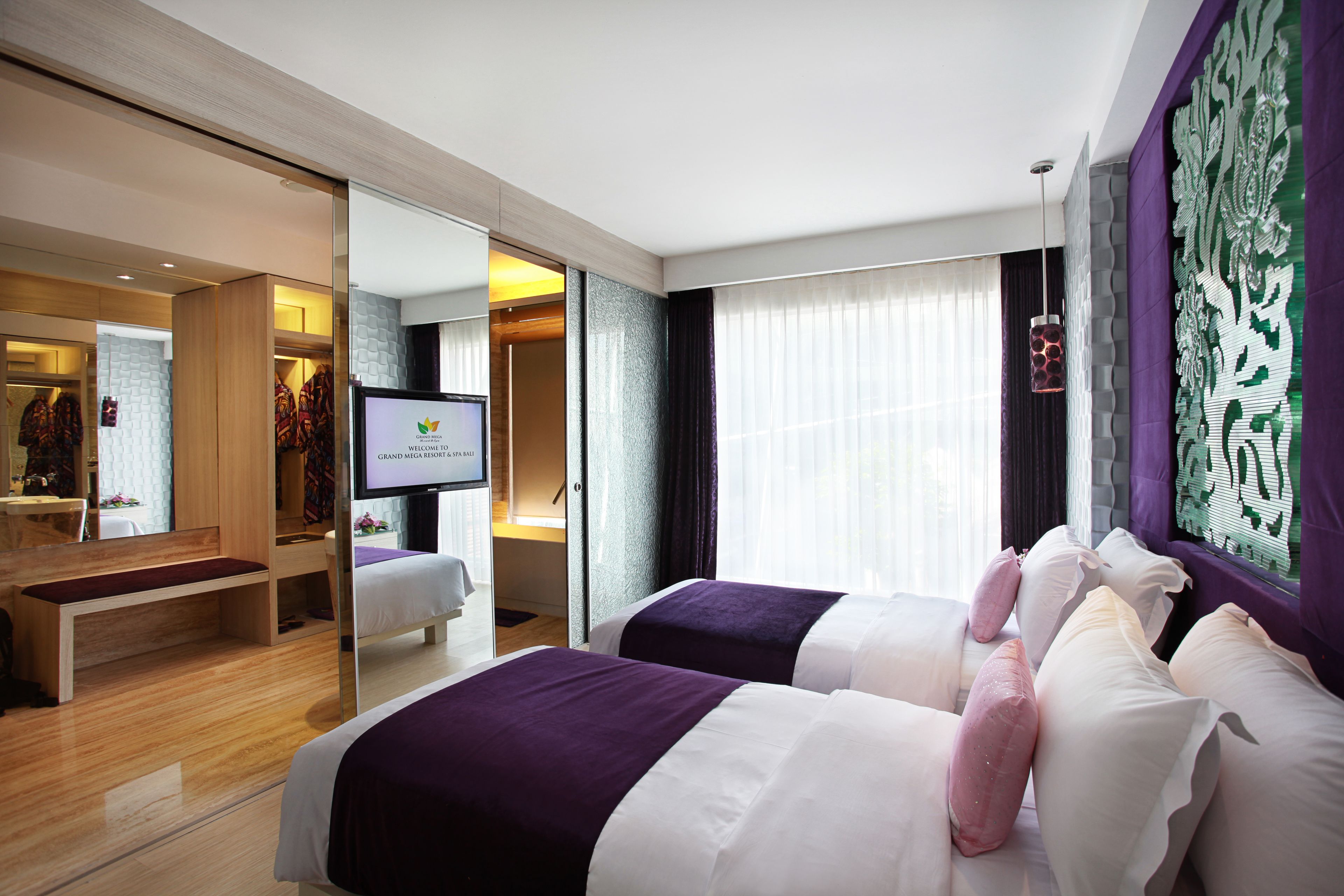 A hotel room with two beds, a TV, a mirror, and a large window with curtains.