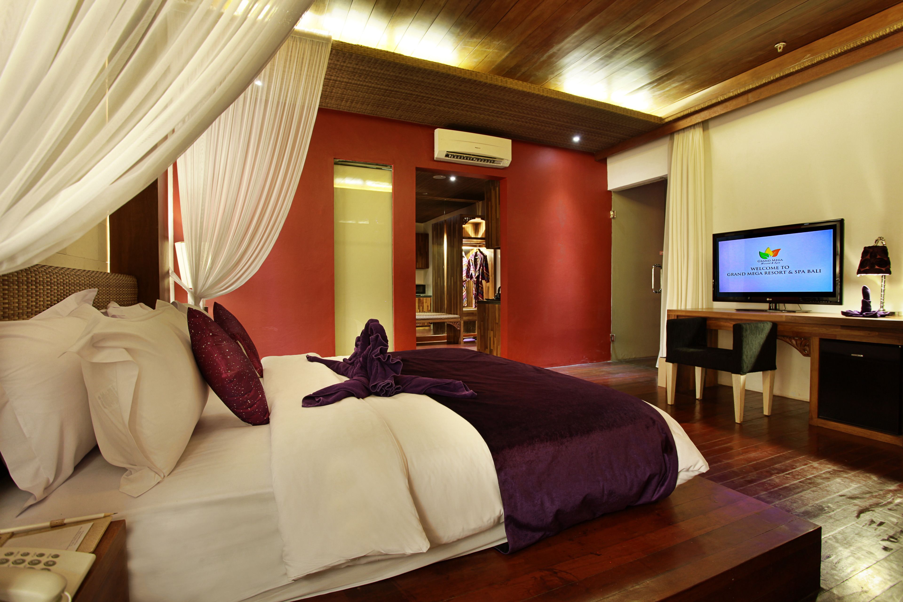 Una habitación de hotel con cama, escritorio, televisor y aire acondicionado.