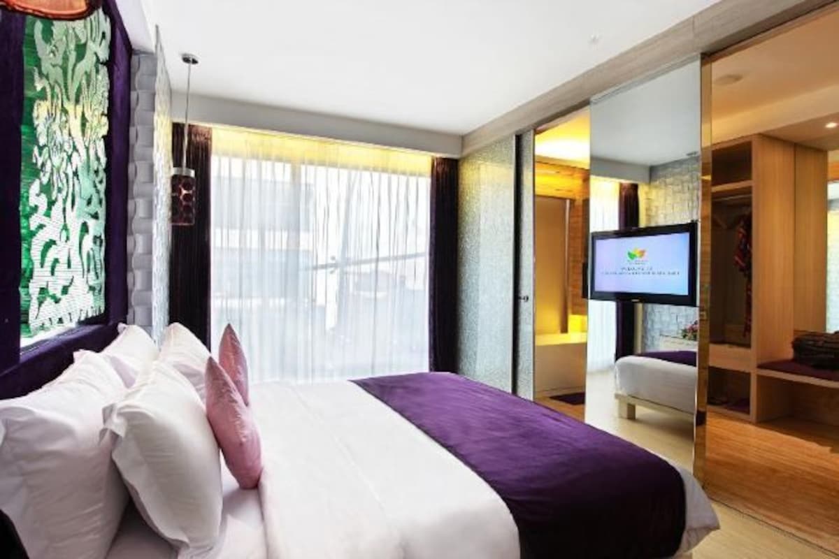 Una habitación de hotel con cama, televisión y vistas al exterior.