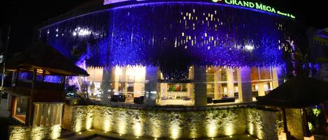 A hotel with a large, illuminated facade and a sign reading "GRAND MEGA Resort & Spa".