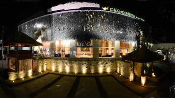 A hotel with a modern facade, a large entrance, and a well-lit outdoor area with a water feature.