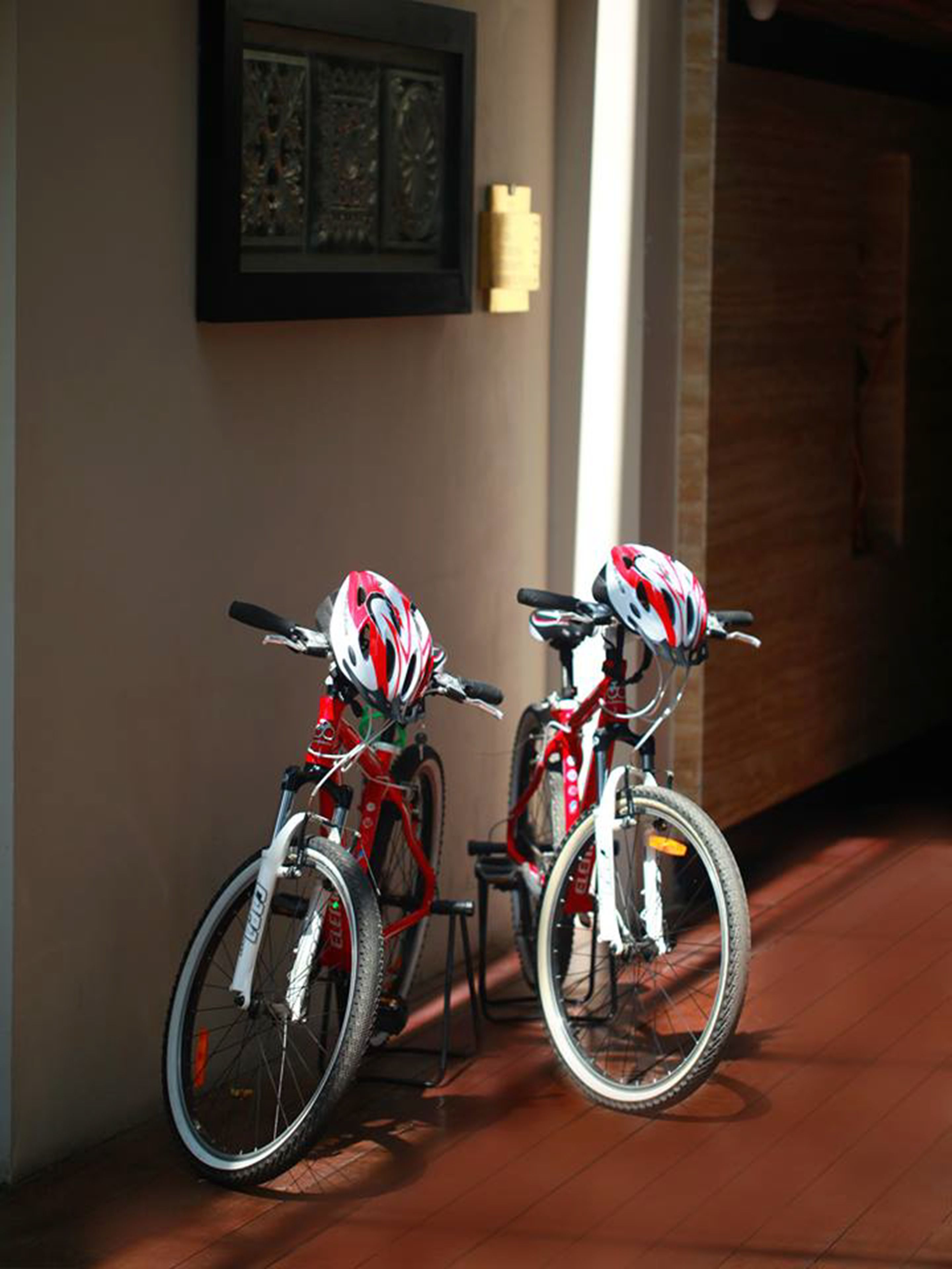 Duas bicicletas com capacetes apoiadas numa parede em um corredor.