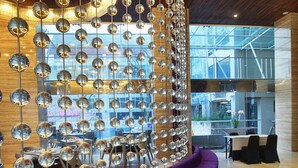 A modern interior with a curved purple seating area, a wooden ceiling, and a wall adorned with spherical mirrors. - Grand Mega Resort & Spa Bali (Kuta)
