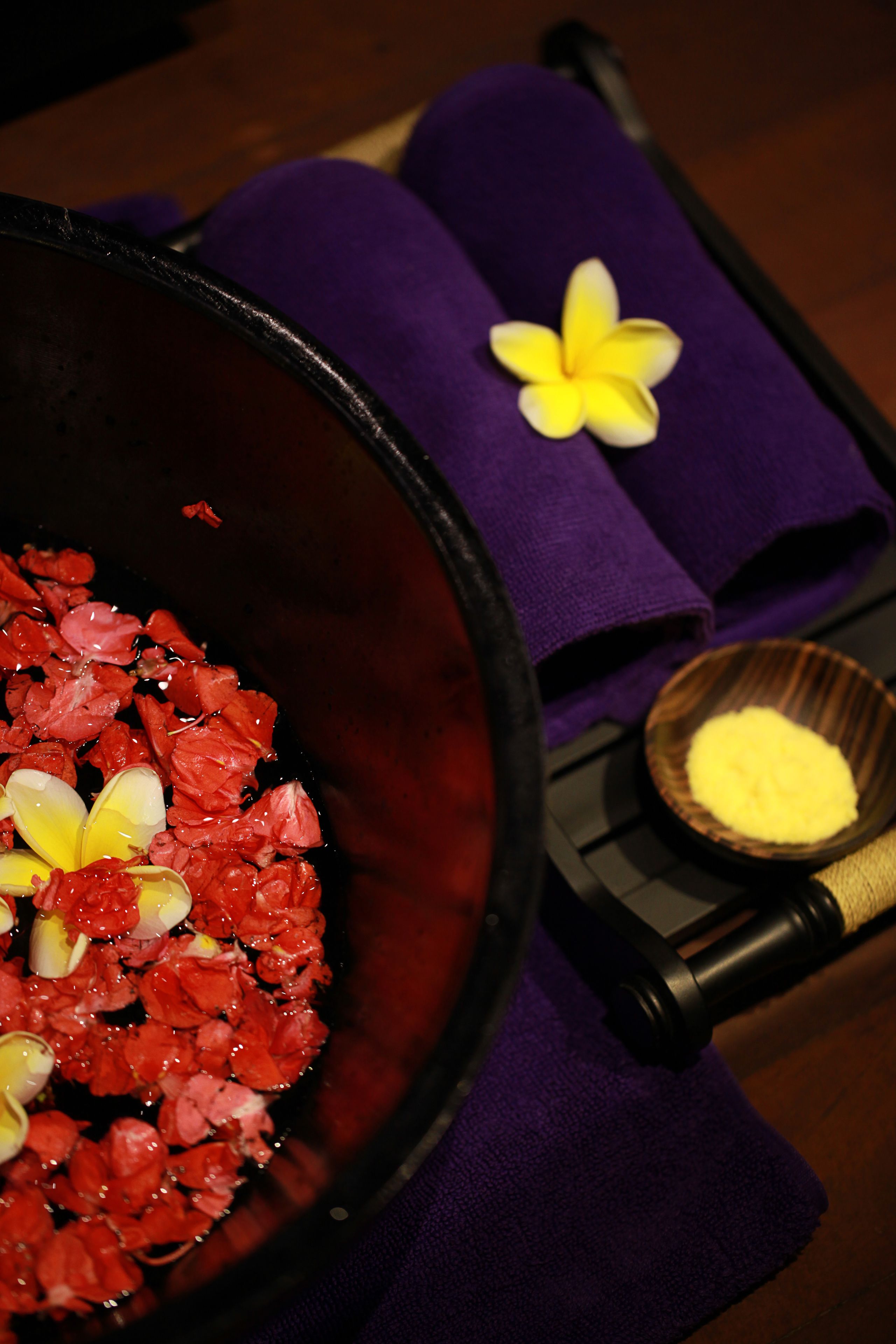 A bathroom with a bathtub filled with rose petals and a flower on the edge.