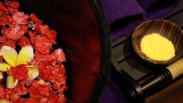 A bathroom with a bathtub filled with rose petals and a flower on the edge.