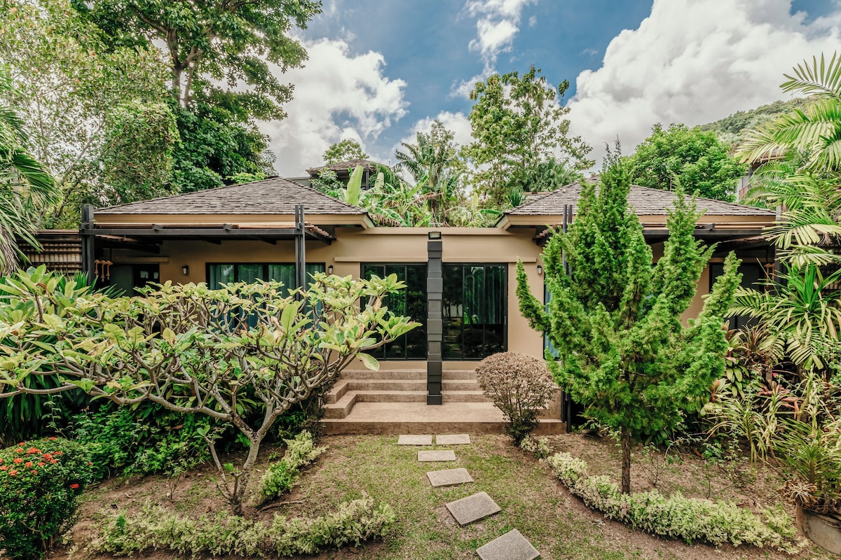 Uma casa moderna com entrada para o jardim, degraus levando à porta e vegetação ao redor.