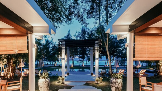 Une terrasse extérieure moderne, dotée d’une pergola, d’espaces aménagés pour s’asseoir et offrant une vue sur la piscine.