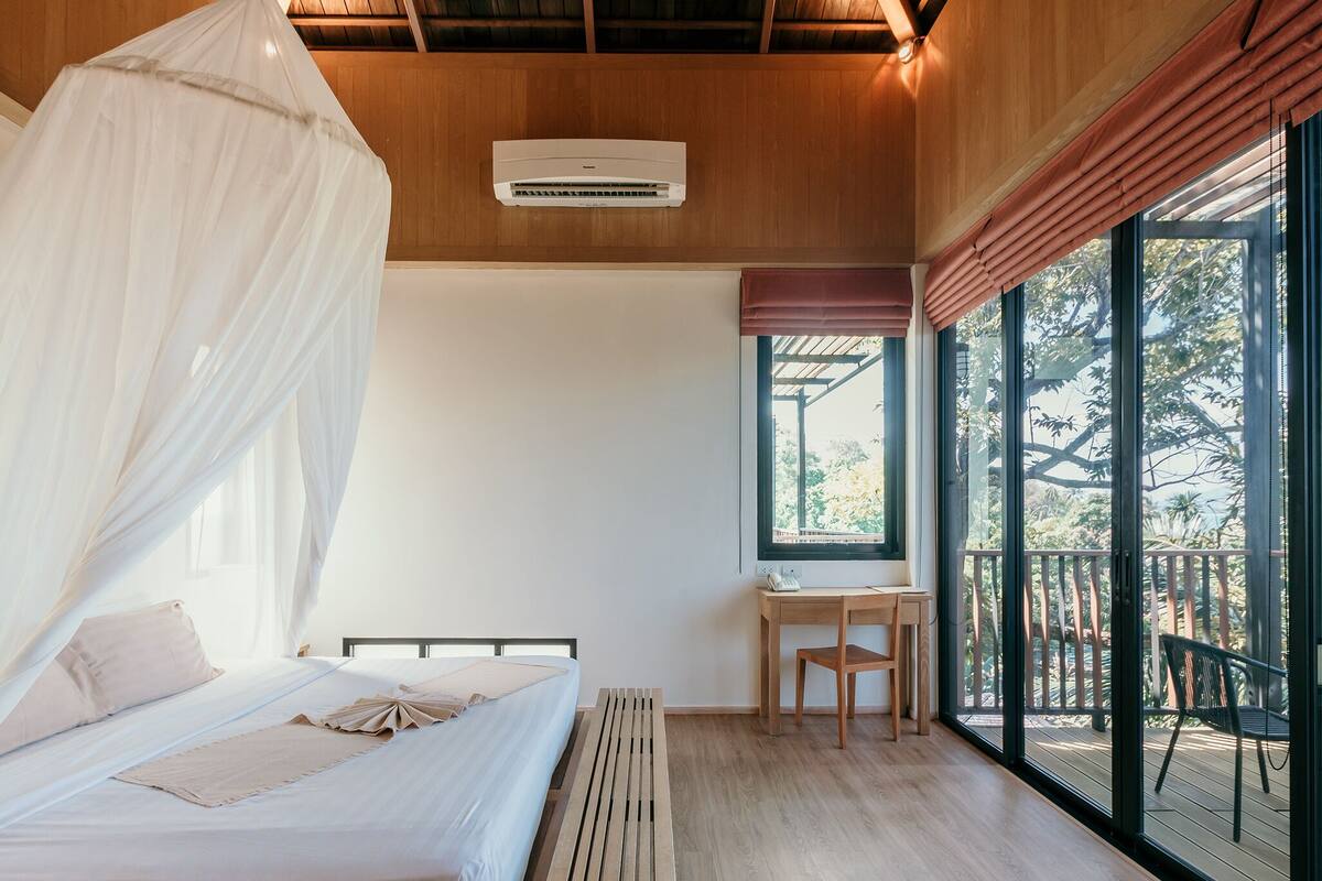 Un dormitorio con cama con dosel, un escritorio y vistas al exterior.