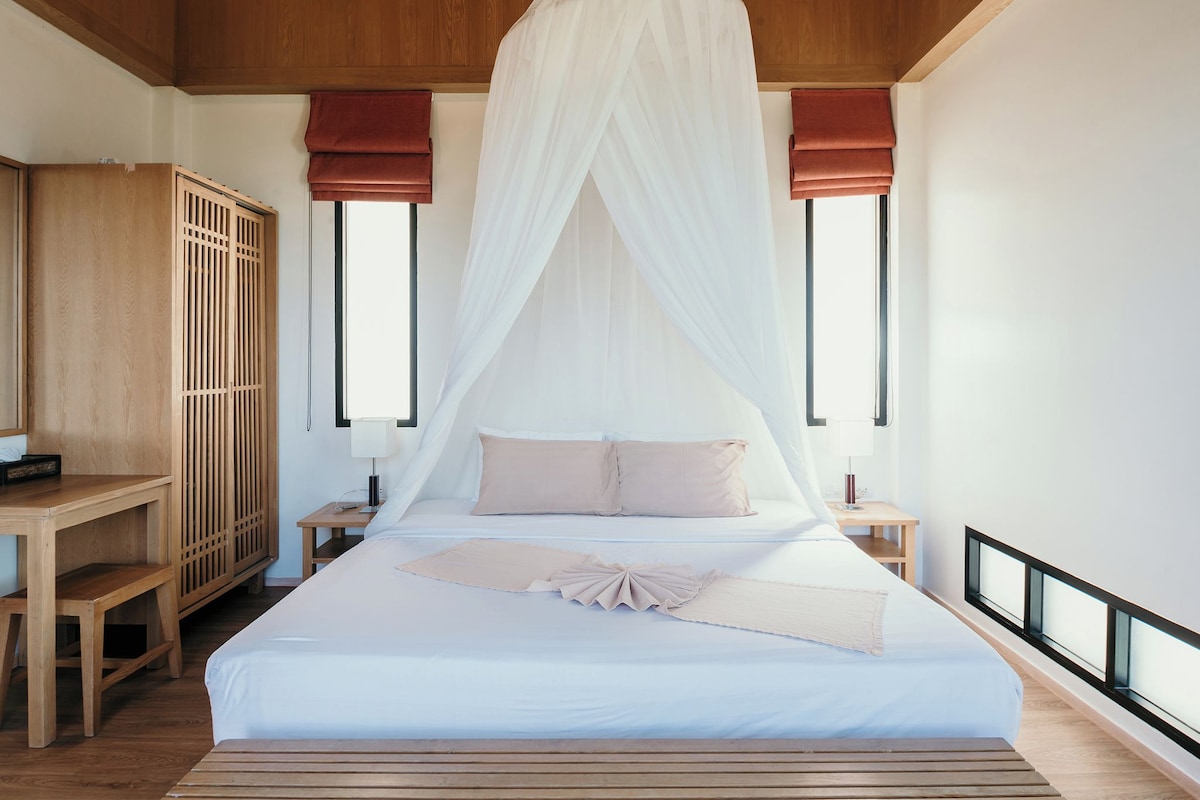 A bedroom with a large bed, wooden headboard, bedside tables, a wardrobe, and a canopy bed.