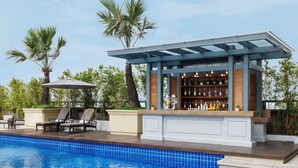 A poolside bar with a wooden deck and a pergola, surrounded by palm trees and a clear sky. - Raffles Makati (Makati)