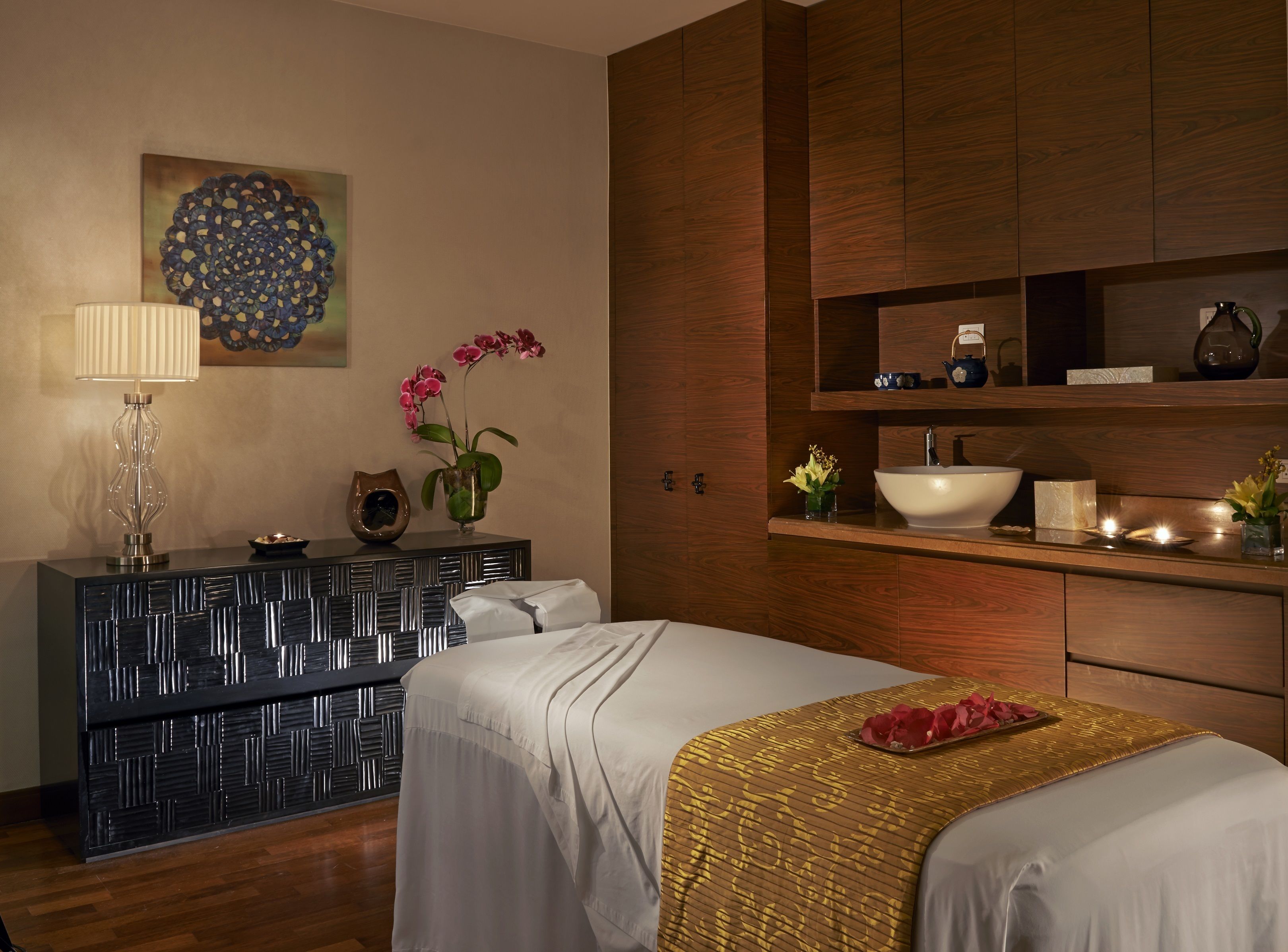 Una habitación de hotel moderna con una cama, una tocador con lavabo, un jarrón decorativo y una obra de arte en la pared.