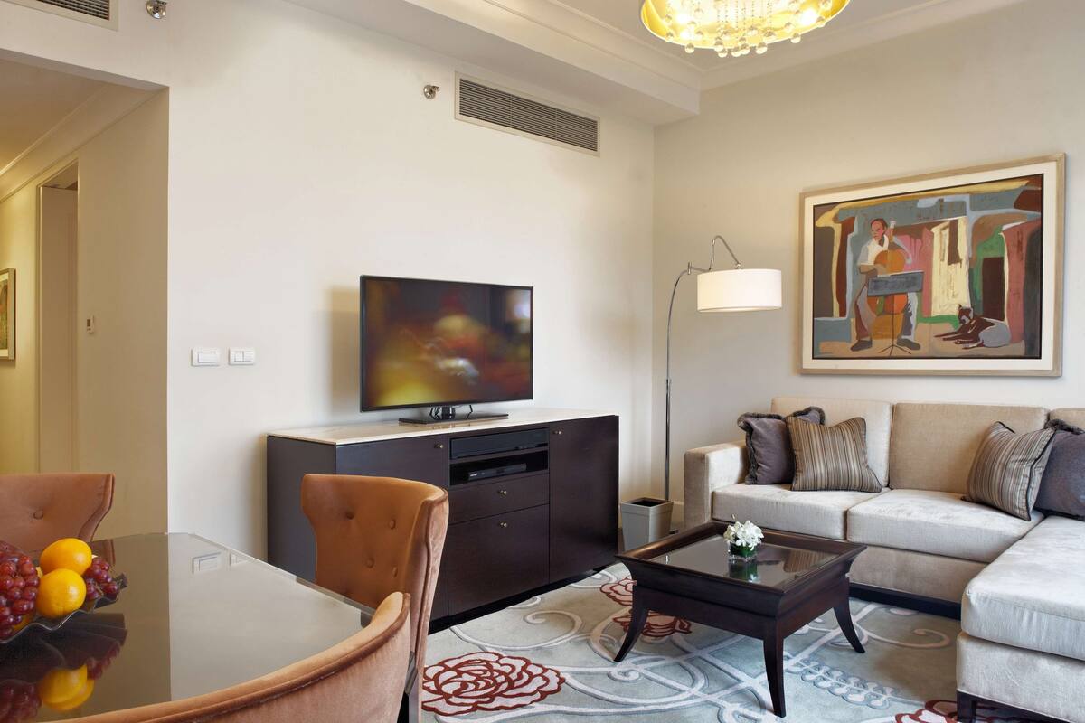Un salon moderne doté d’un téléviseur à écran plat, d’un canapé, d’une table basse et d’un coin repas avec des chaises et une table en verre.
