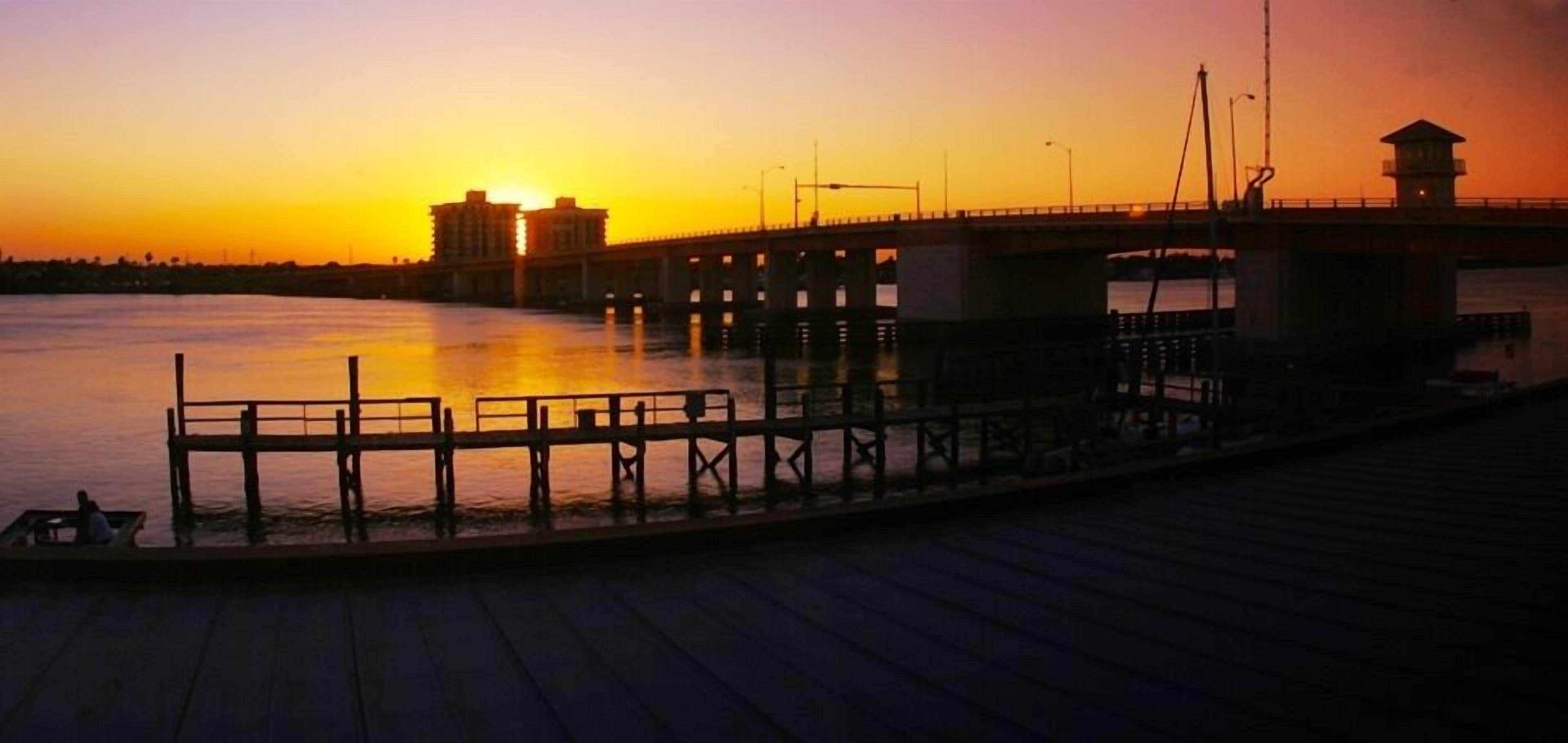 A pier with a bridge over water during sunset.