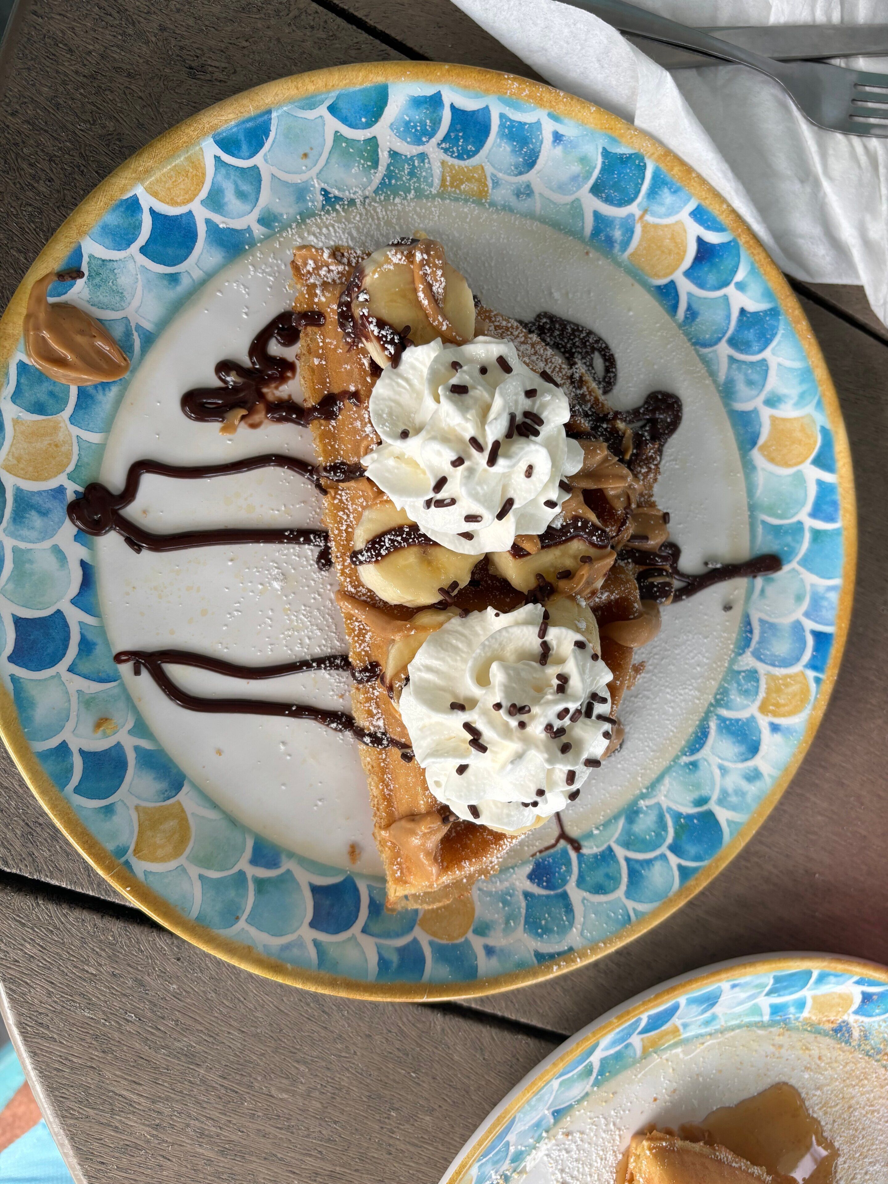 Un plato con un postre cubierto de crema batida y grageas de chocolate.