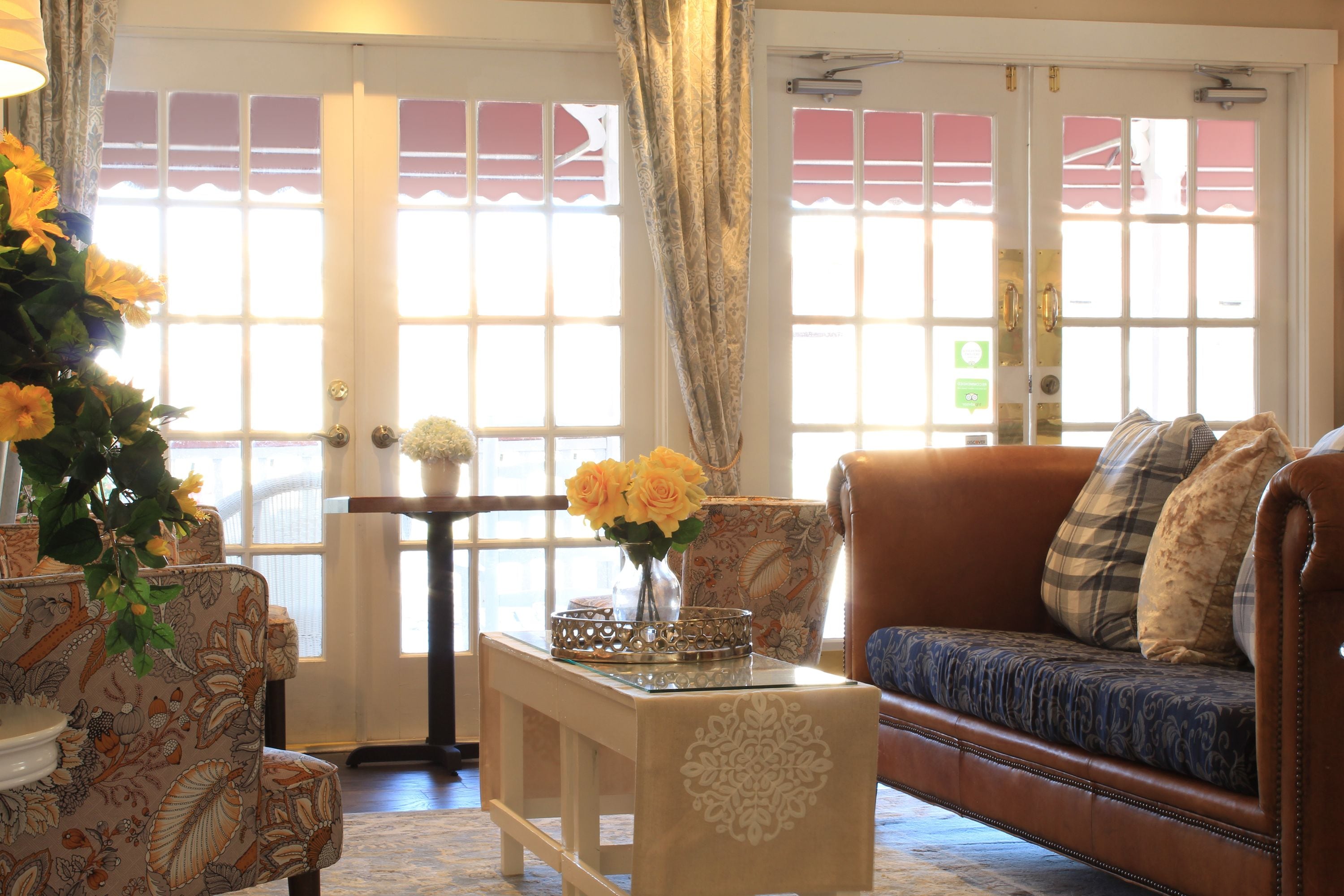 Uma sala de estar com sofá, poltronas, mesa de centro com um vaso de flores e um tapete estampado.