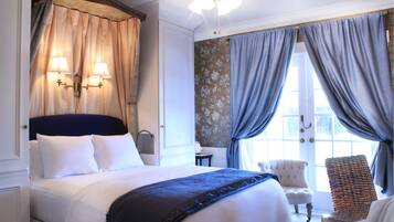 A hotel room with a large bed, two bedside lamps, a chair, and a view of the outdoors.