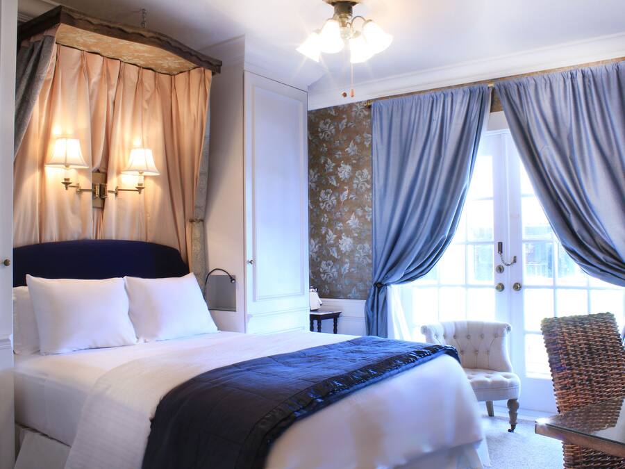 A hotel room with a large bed, two bedside lamps, a chair, and a view of the outdoors.