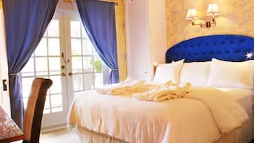 A bedroom with a large bed, a chair, a door with curtains, and wall sconces.