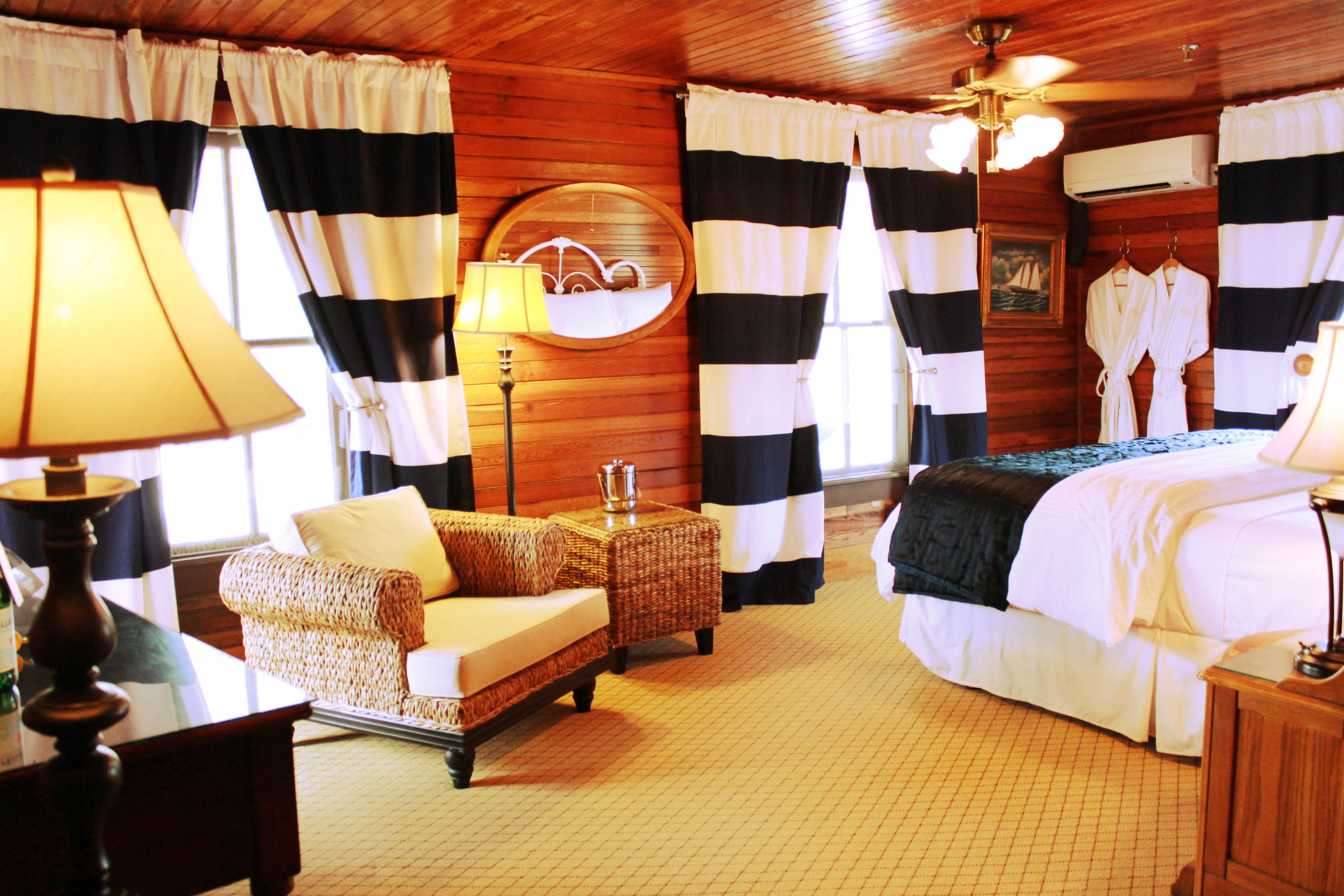 A room with a bed, a sofa, a lamp, and a mirror.
