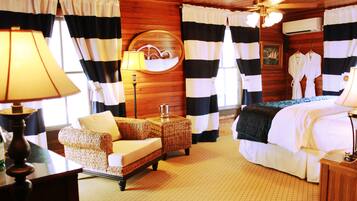 A room with a bed, a sofa, a lamp, and a mirror.