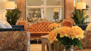 A luxurious living room with a tufted sofa, patterned armchairs, a coffee table, and a vase of flowers.