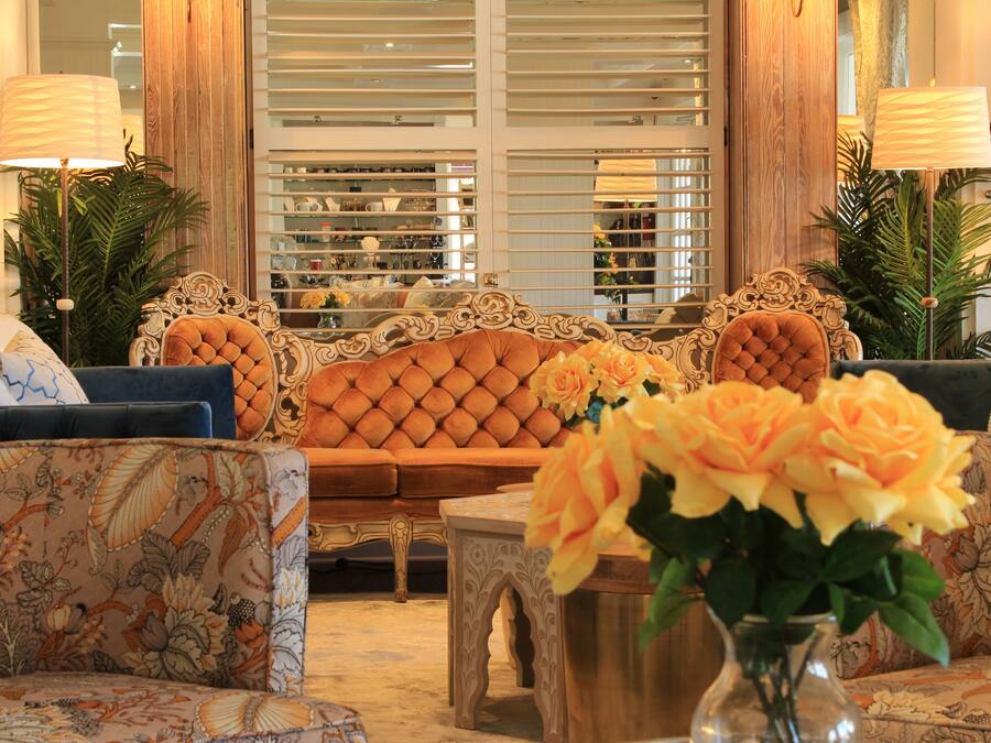 A luxurious living room with a tufted sofa, patterned armchairs, a coffee table, and a vase of flowers.