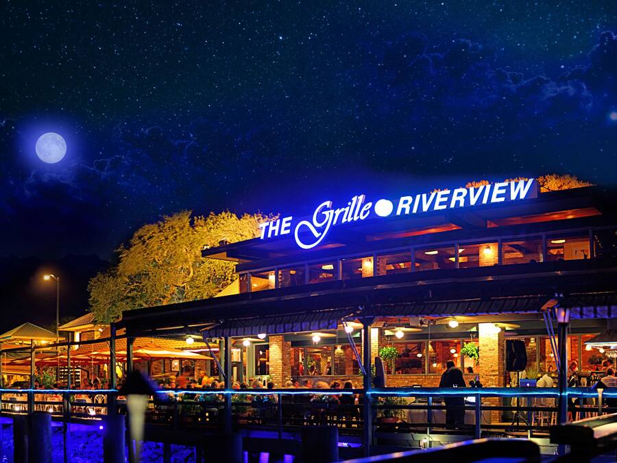 A waterfront restaurant named "The Grille Riverview" with outdoor seating and a view of the water.